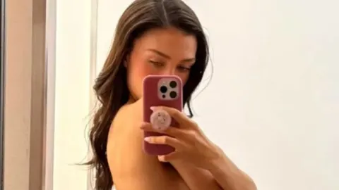 Nicola Peltz Beckham snima selfie u ogledalu s tamnom kosom.