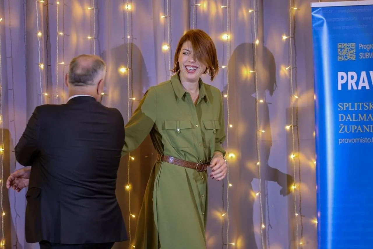 Blanka Vlašić se smije dok se pozdravlja s muškarcem ispred ukrasnih lampica.