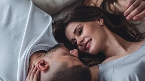 Nasmijano lice žene i muškarca koji leže u krevetu