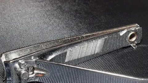 Srebrna metalna grickalica za nokte s vidljivom malom rupom na stražnjoj strani.