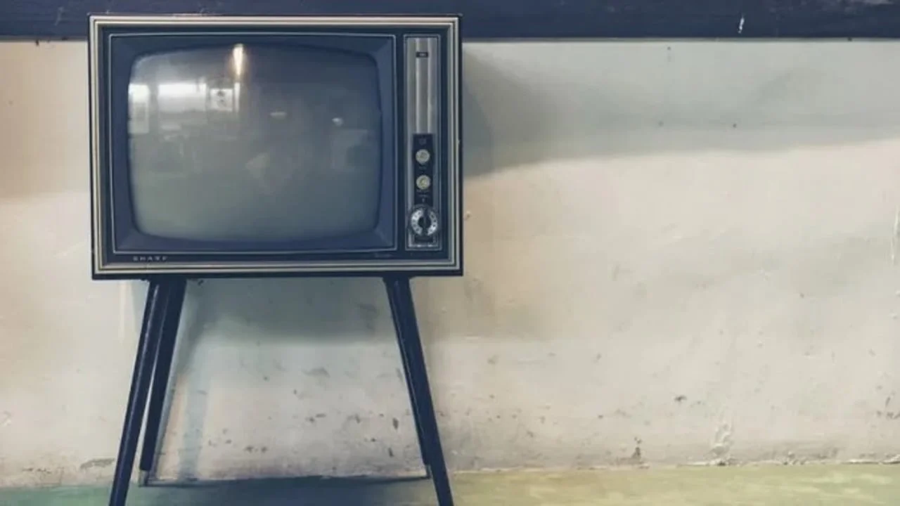 Stari televizor s drvenim okvirom na visokim crnim nogarama.