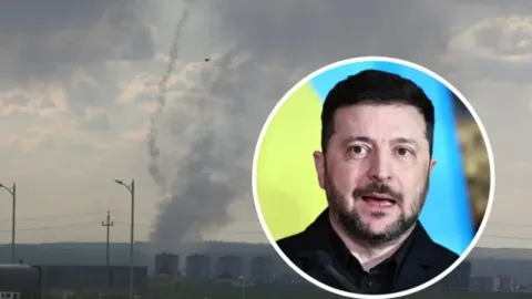 Portret Volodimira Zelenskog ispred scene s dimom i tragovima projektila na nebu.