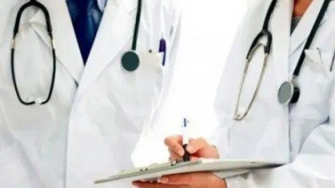 Dva liječnika u bijelim kutama sa stetoskopima pišu po medicinskom kartonu.