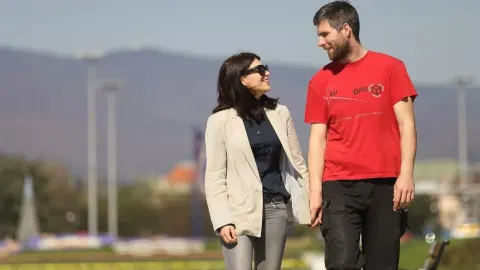 Mladi par u šetnji na otvorenom razgovara i smiješi se