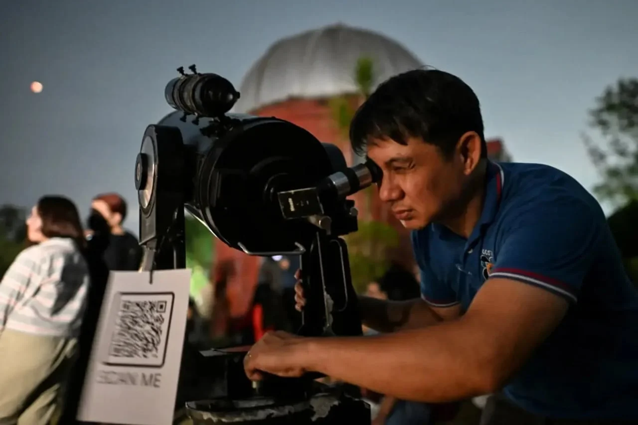 Muškarac gleda kroz veliki astronomski teleskop u zvjezdarnici