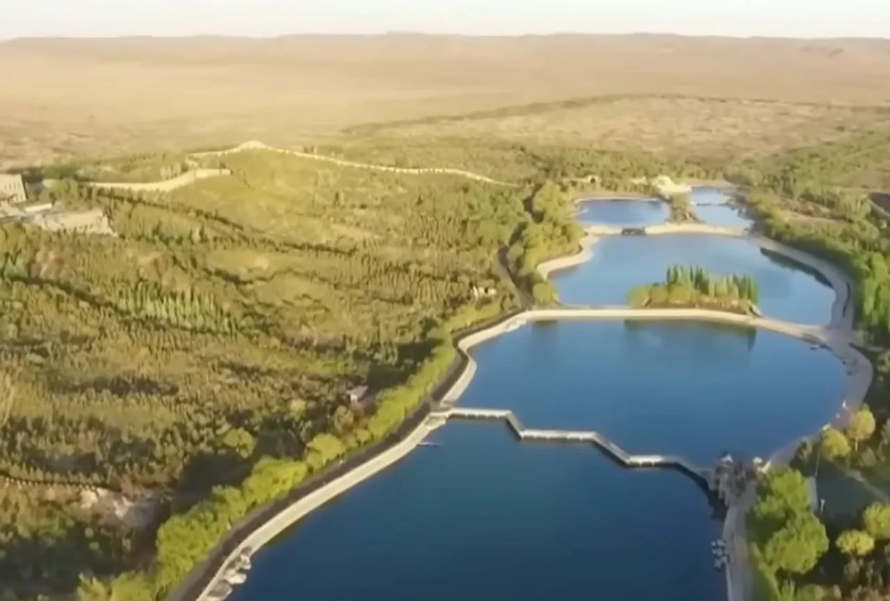 Zračni prikaz niza umjetnih jezera i gustog zelenila usred sušnog krajolika.