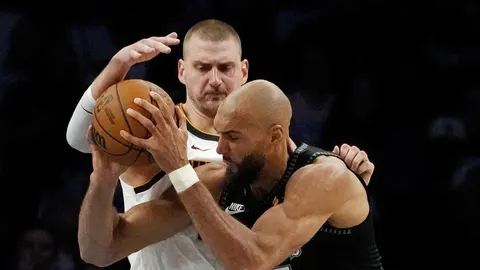 Nikola Jokić i Rudy Gobert u bliskom kontaktu tijekom borbe za loptu na NBA utakmici.