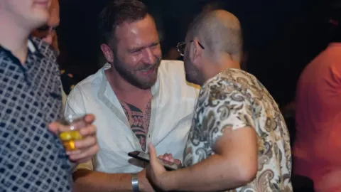 Ivan Pažanin s kratkom frizurom i bradom u razgovoru na društvenom događaju.