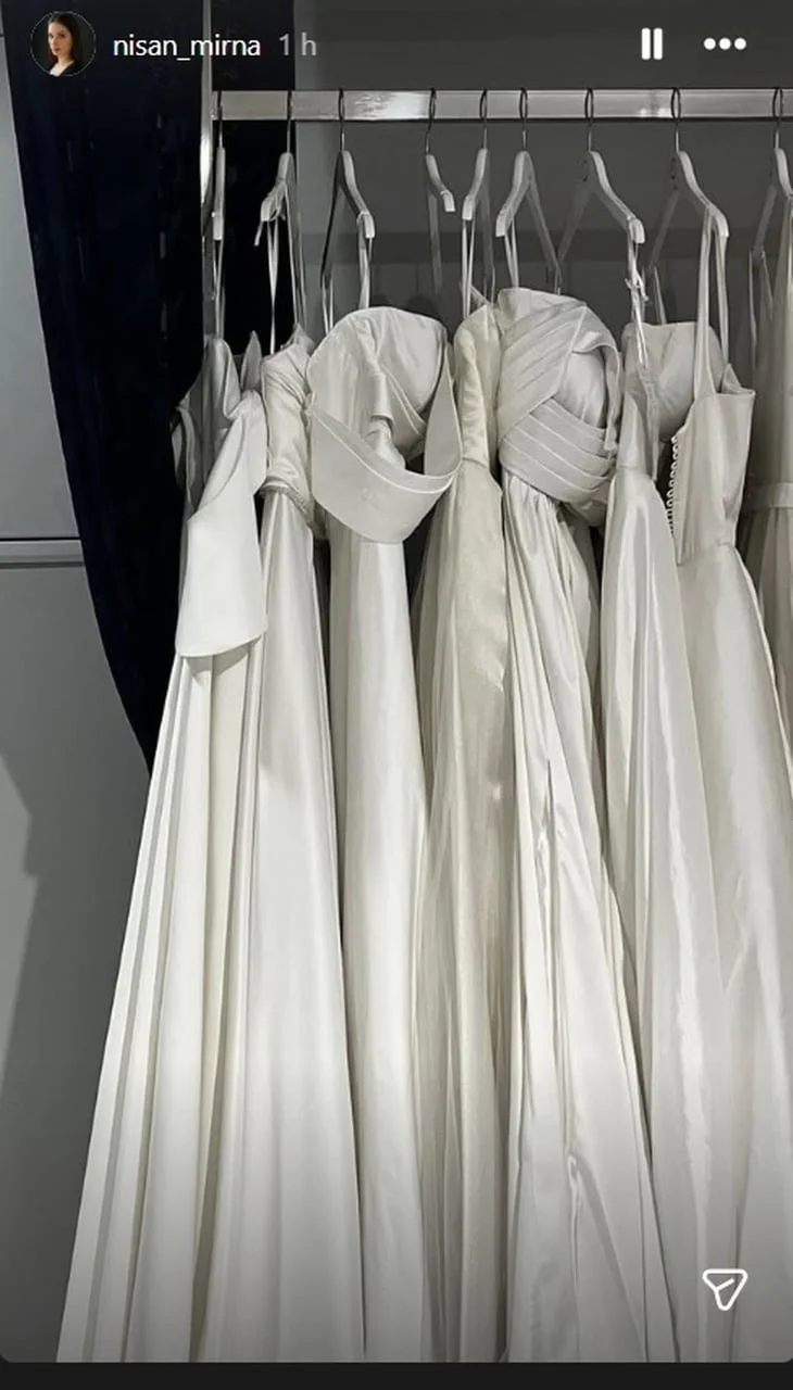 Niz bijelih vjenčanica na vješalicama u butiku