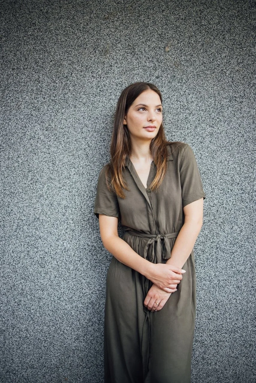 Mirna Mihelčić u maslinastoj haljini stoji uz sivi zid