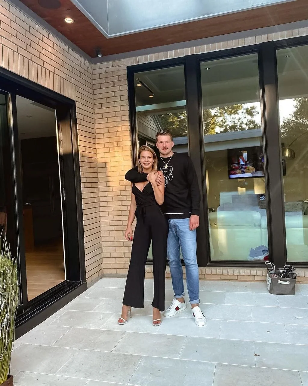 Luka Dončić grli Anamariju Goltes ispred moderne kuće s velikim staklenim stijenama.