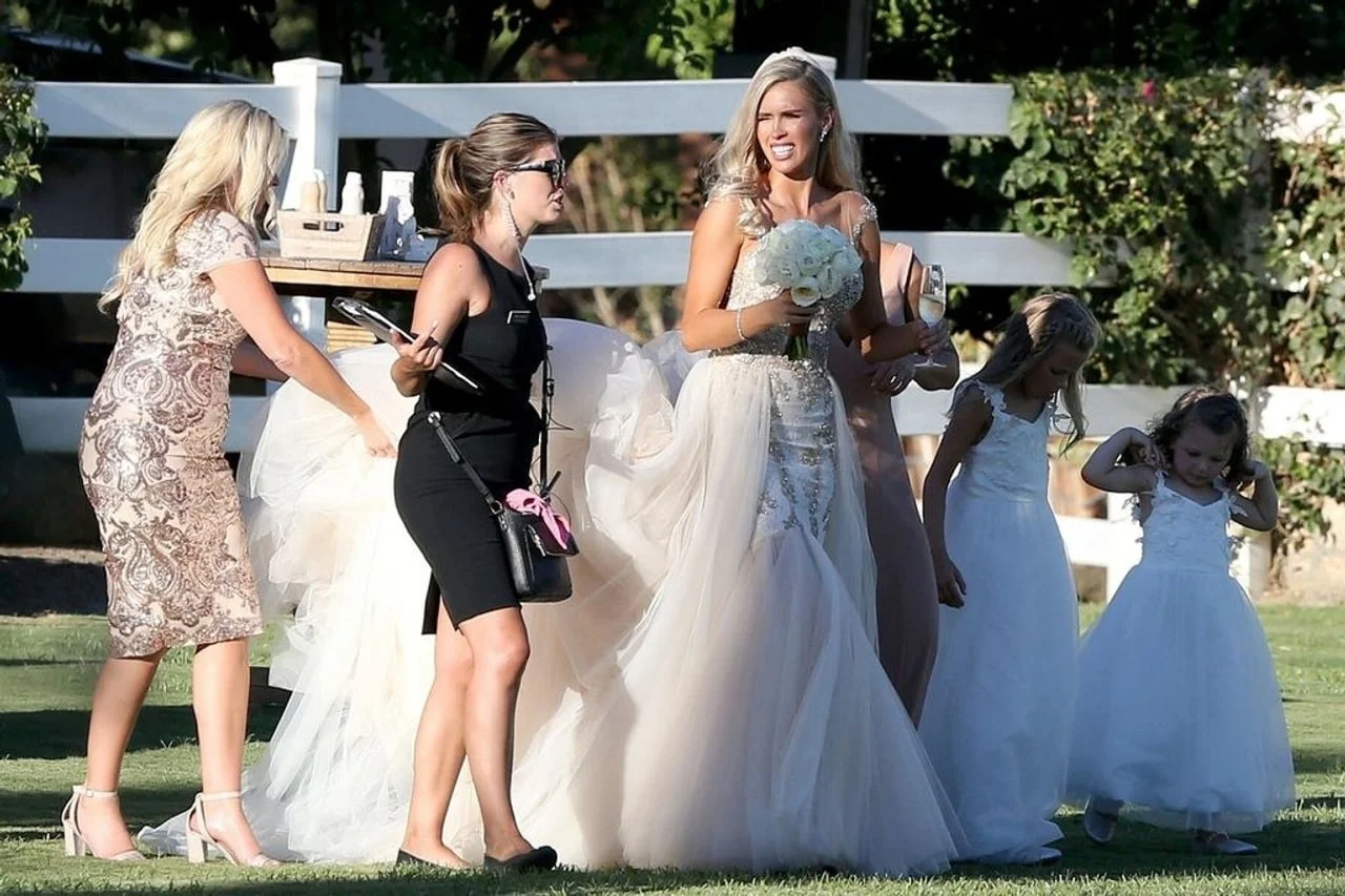 Mladenka Kayla Rae Reid u raskošnoj vjenčanici okružena pomagačima na travi.