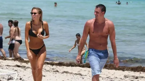 Ryan Lochte i Kayla Rae Reid šeću pješčanom plažom u kupaćim kostimima.
