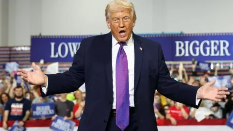 Donald Trump u tamnom odijelu s ljubičastom kravatom govori na predizbornom skupu