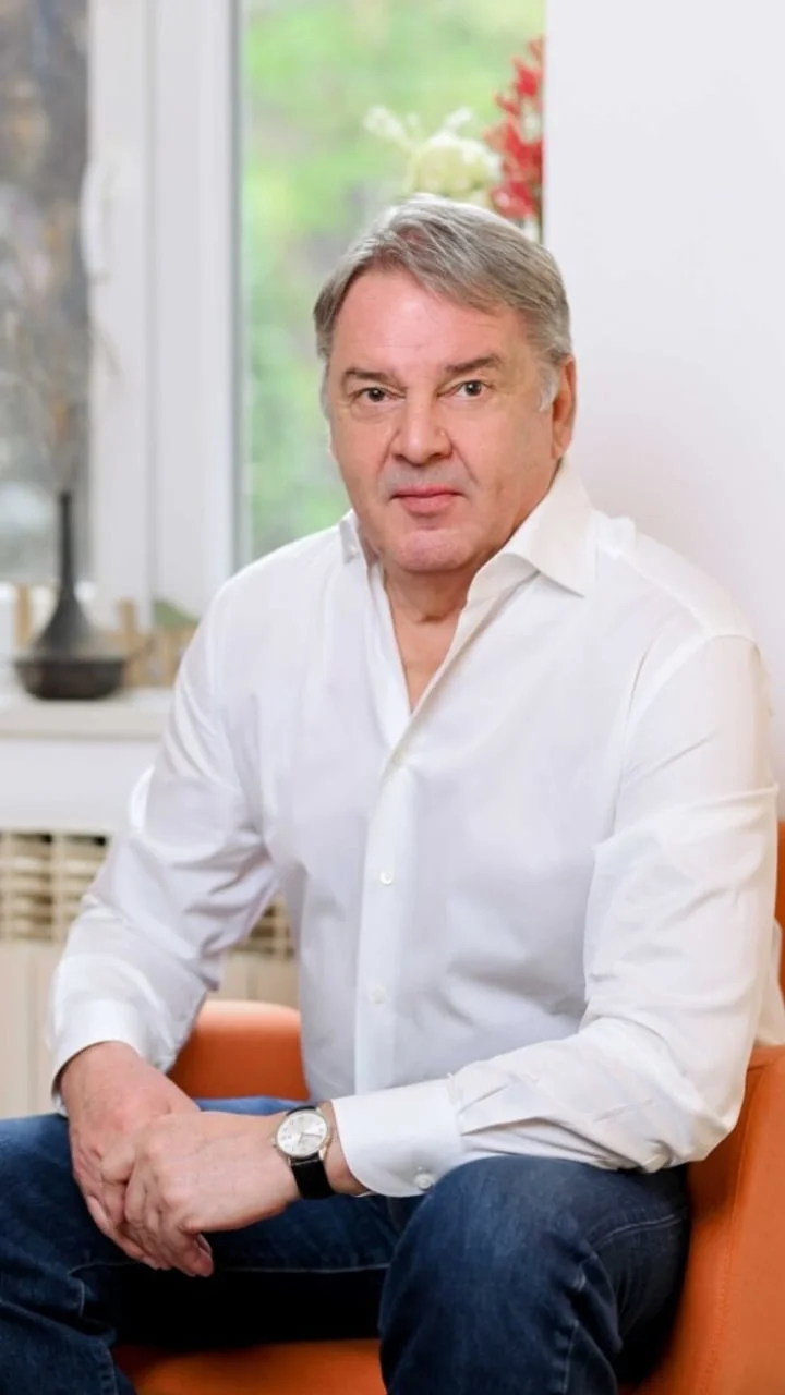 Portret muškarca u bijeloj košulji koji sjedi na narančastom stolcu