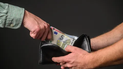 Ruka vadi novčanice eura iz crnog kožnog novčanika koji drži druga osoba.