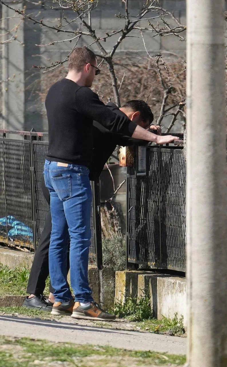 Muškarac u crnom naslonjen na ogradu s glavom u rukama