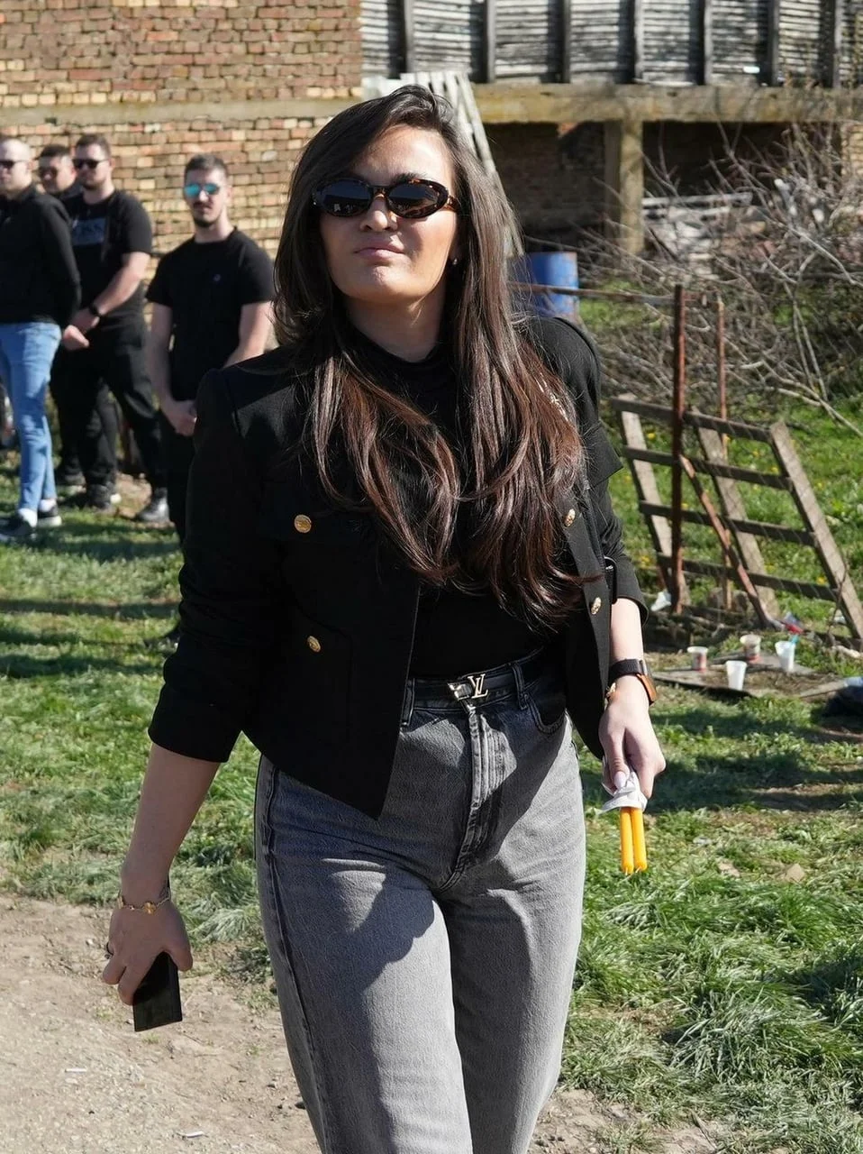 Žena s tamnim naočalama i žutim svijećama u ruci