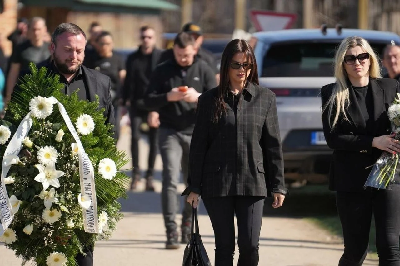 Žena u crnom sa sunčanim naočalama nosi bijeli vijenac