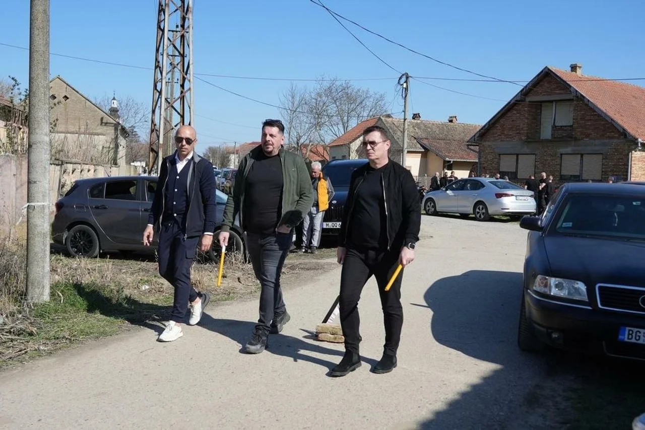 Tri muškarca hodaju cestom noseći žute svijeće