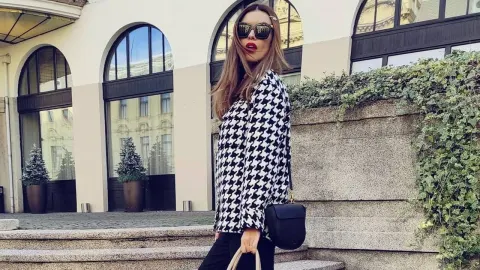 Anita Dujić Broadfoot u crno-bijelom sakou sa sunčanim naočalama ispred zgrade.