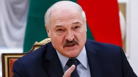 Aleksandar Lukašenko govori za govornicom ispred bjeloruske zastave.