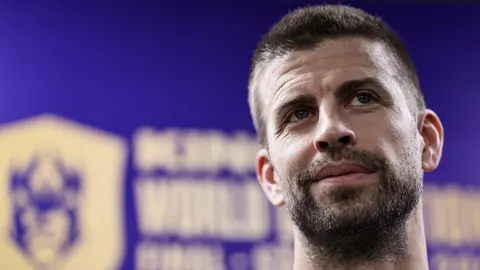 Kratko ošišan Gerard Pique s bradom gleda prema gore ispred tamnoplave pozadine.