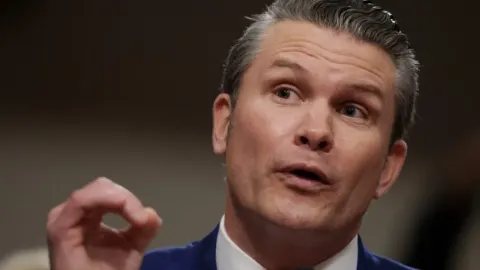 Krupni kadar Petea Hegsetha tijekom govora s podignutom rukom