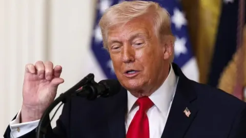 Donald Trump govori za mikrofonom ispred američke zastave