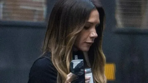 Victoria Beckham u krupnom planu dok drži naočale i piće