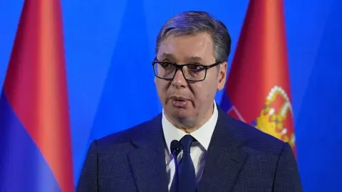 Aleksandar Vučić govori ispred srbijanskih zastava.