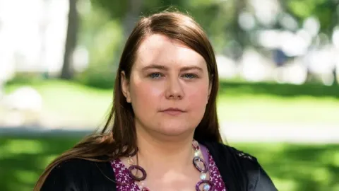 Portret Natasche Kampusch s ozbiljnim izrazom lica na otvorenom.