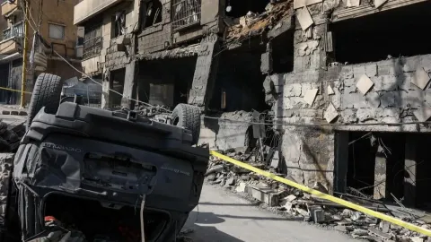 Prevrnuti automobil ispred razrušene višekatnice u naseljenom području.