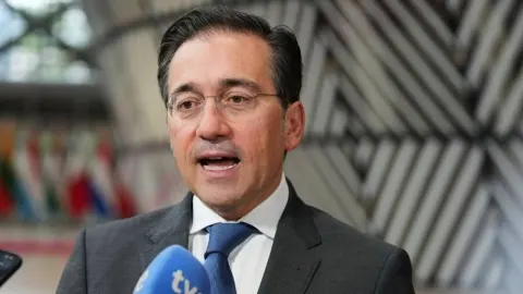 José Manuel Albares s naočalama govori pred mikrofonima novinara u Briselu.