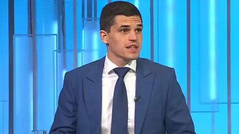 Nemanja Zavišić u plavom odijelu i kravati govori tijekom televizijskog gostovanja.