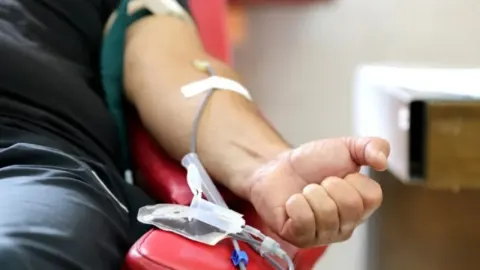 Osoba koja dobrovoljno daruje krv kroz medicinsku iglu i cijev u ruku.