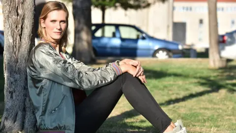 Barbara Jelić sjedi u parku naslonjena na stablo u ležernoj odjeći.