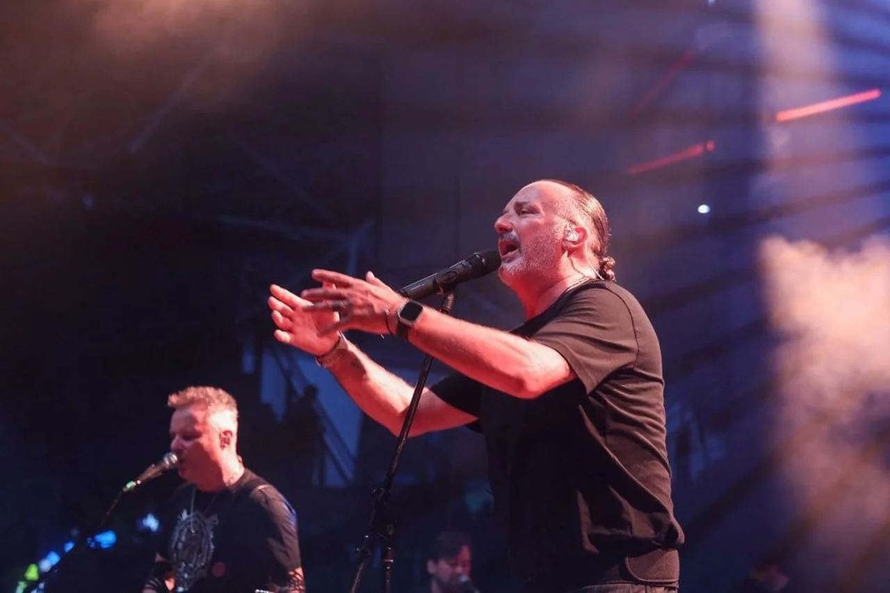 Tony Cetinski s mikrofonom u ruci gestikulira prema publici na koncertu.