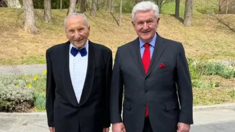 Ivica Todorić i njegov otac Ante stoje nasmijani u svečanim odijelima na otvorenom.