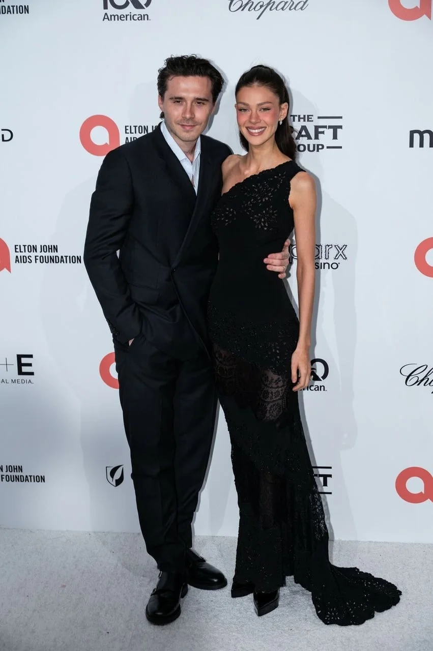 Portret Brooklyna Beckhama i Nicole Peltz na crvenom tepihu u elegantnoj odjeći.