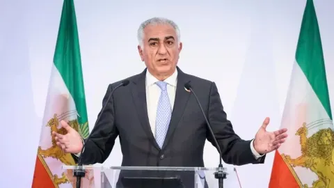 Reza Pahlavi drži govor za govornicom ispred iranskih zastava