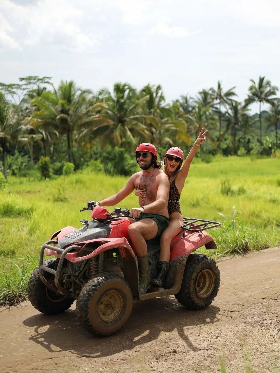 Par se vozi na crvenom quadu kroz tropski krajolik